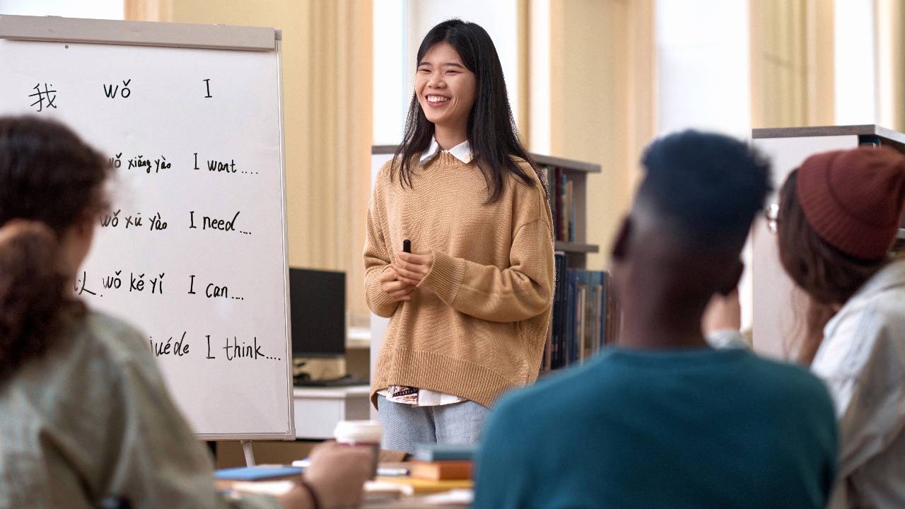 Portrait of smiling young Asian woman teaching Chinese language to diverse group of students copy space